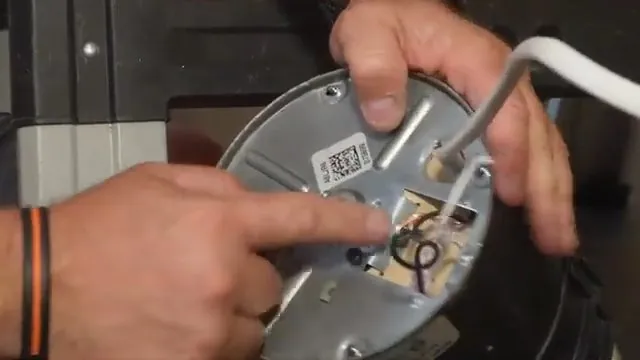 Hands pointing at the underside of a garbage disposal where an Allen key is seated in the motor