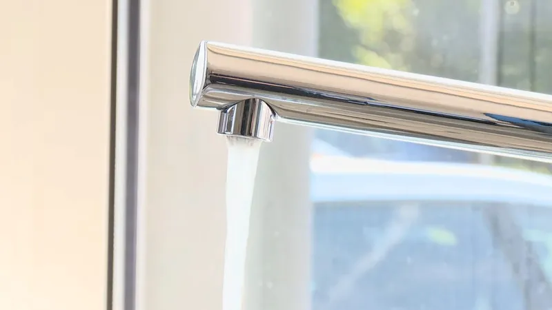 Water running from a chrome faucet beside a window
