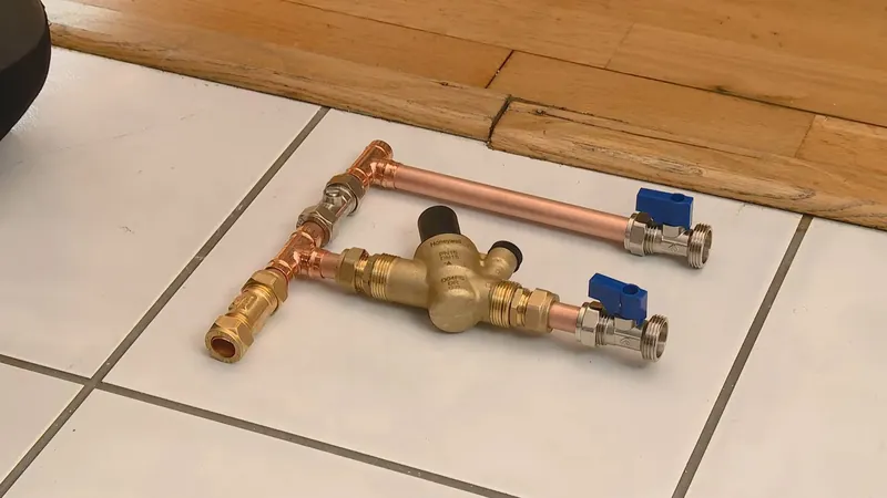 Copper pipe and brass valves laid out on a white tile floor