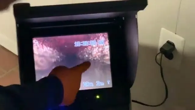 A hand pointing at a camera monitor showing the inside of a pipe