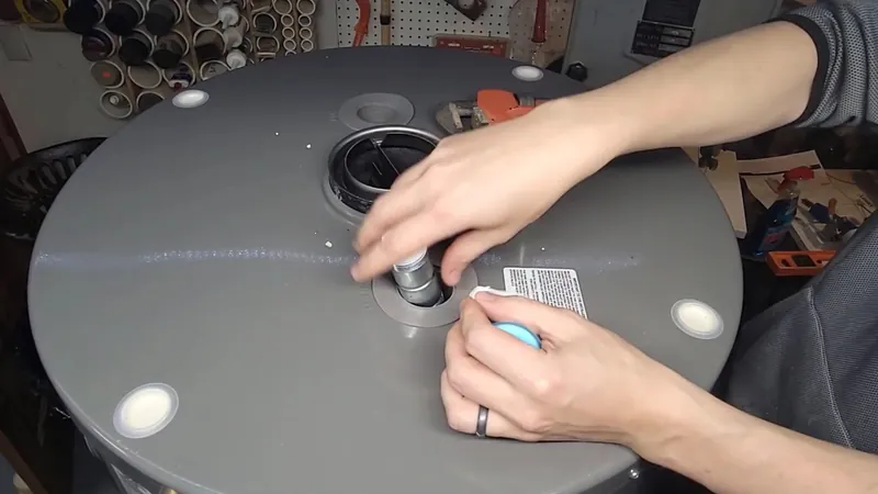 Hands working on the top fittings of a gray water heater tank