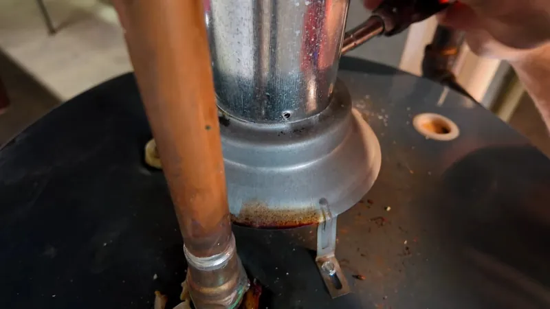 A metal vent pipe and a copper line rising from the top of a water heater