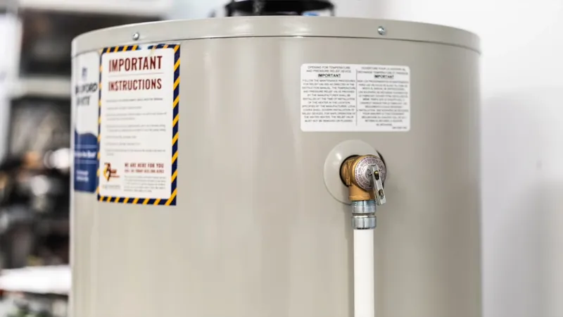 A close view of a water heater tank showing its warning label and a supply connection